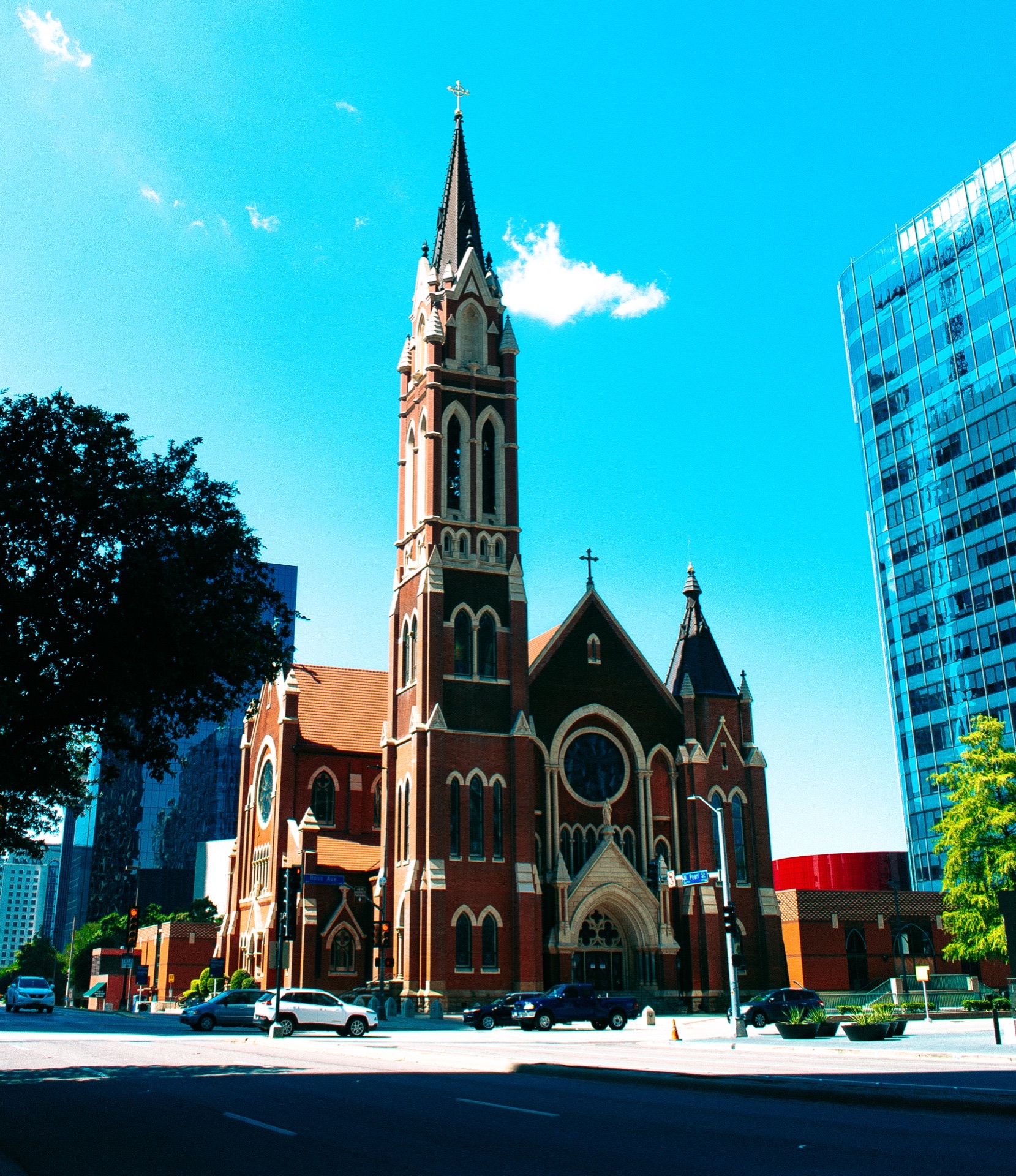 A red-brick gothic cathedral spire against a bright sky, from the Aerial study, frame one