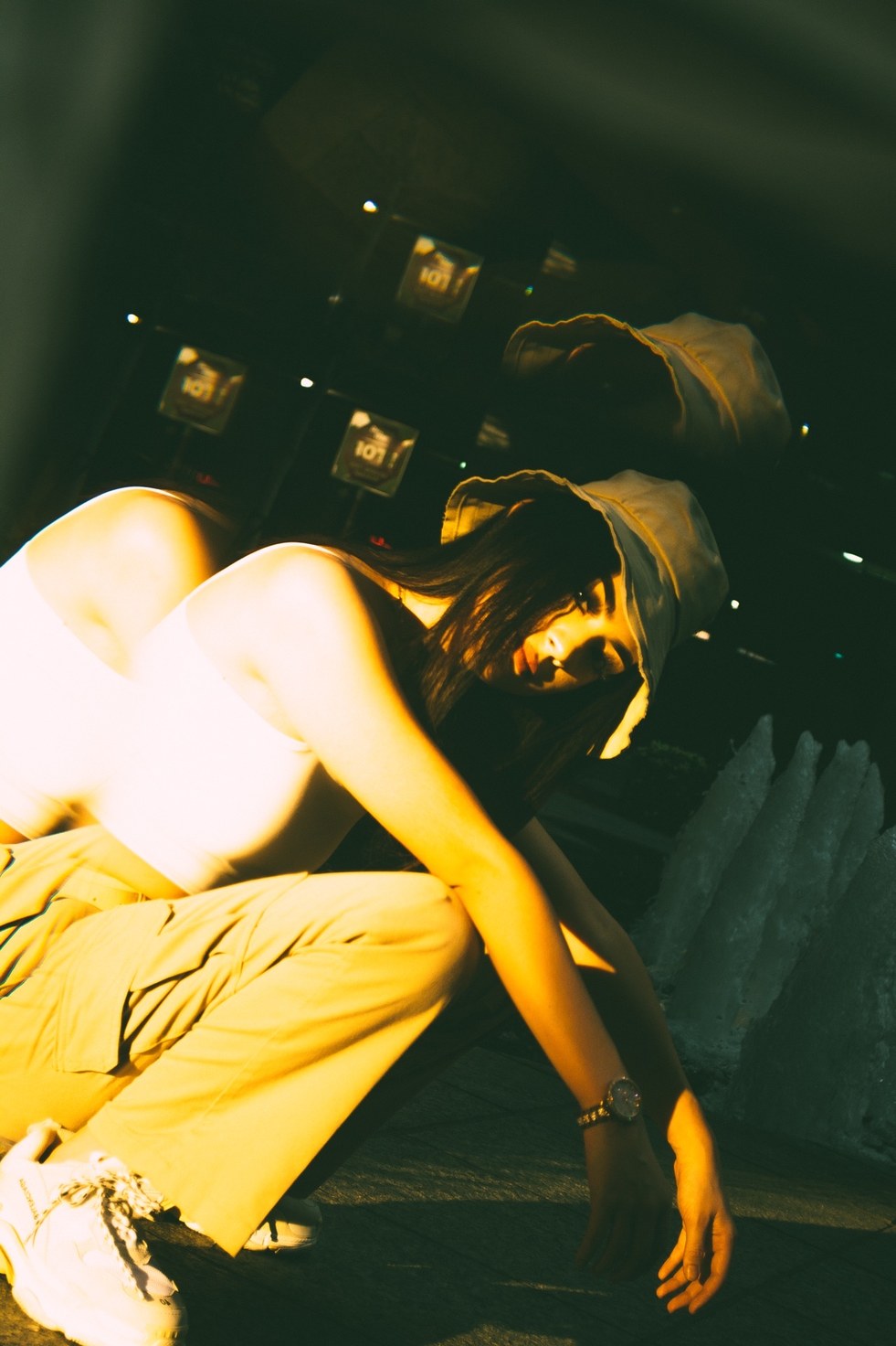 A tilted frame of a crouching figure reaching for the pavement, a reflected hat ghosting above — from the BALENCI sequence