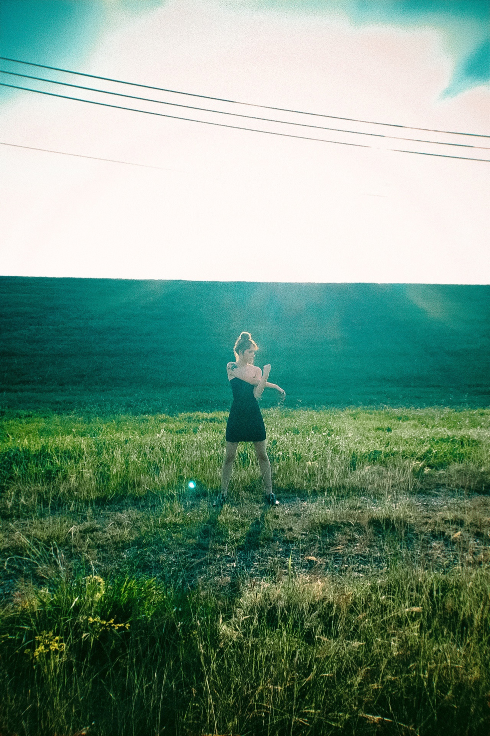 Rouge study — a black dress in a green field under a low sun