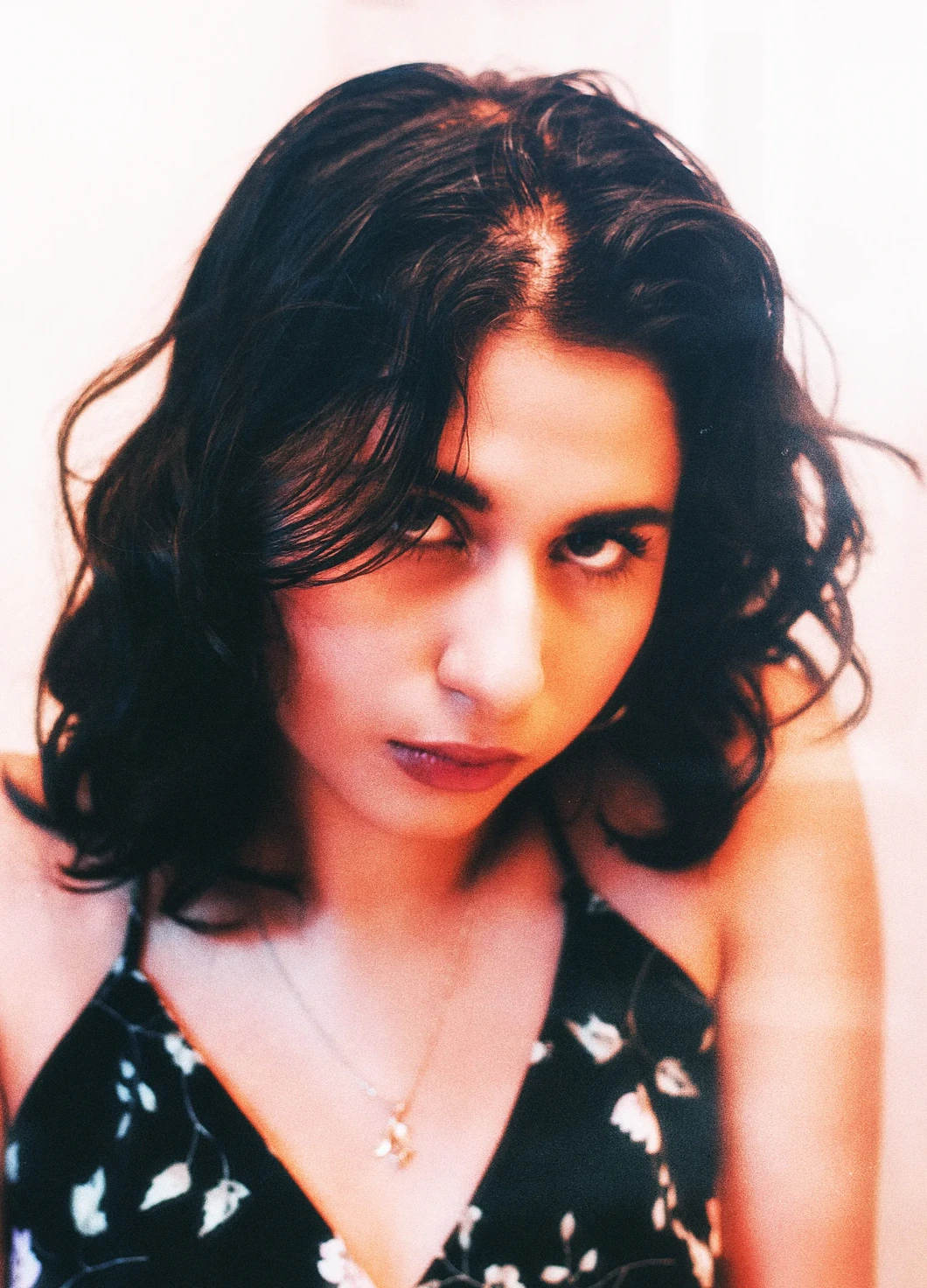 A portrait with wet dark curls and a black floral slip, looking up into the lens — Tunnel Vision study